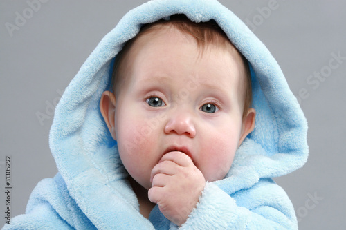 Adorable baby boy in a blue bathrobe