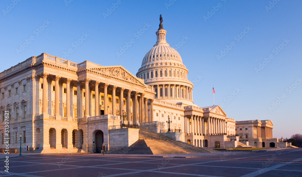 Fototapeta premium Rising sun illuminates the front of the Capitol building in DC