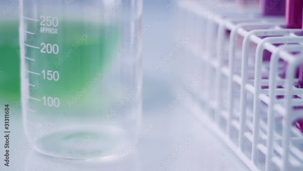 Hands pouring liquid from test tubes into beaker in research lab Hands pouring liquid from test tubes into beaker in research lab