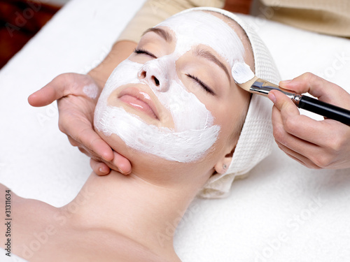 Woman receiving facial mask at beauty salon
