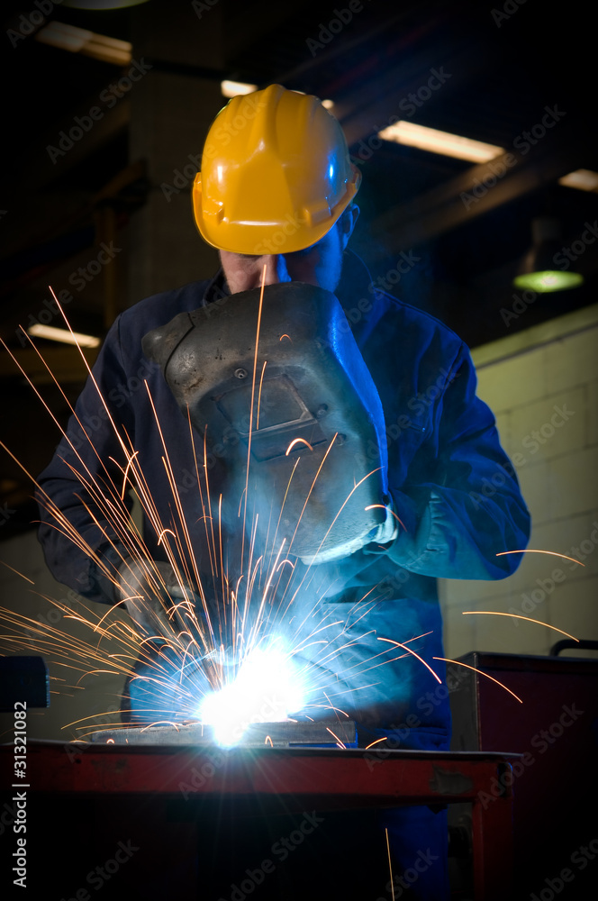 Worker making sparks while welding steel. - obrazy, fototapety, plakaty 