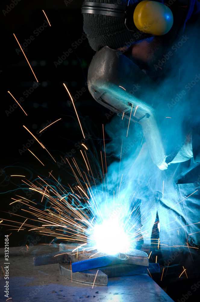 Worker making sparks while welding steel. Worker making sparks while welding steel.