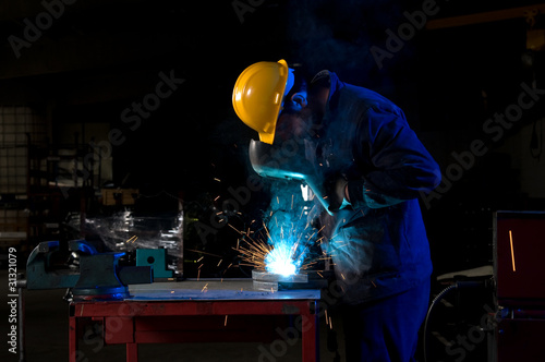 Billede på lærred Worker making sparks while welding steel.