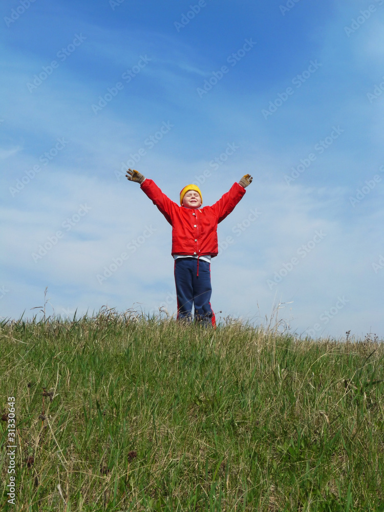 The boy is raising his hands against the blue sky