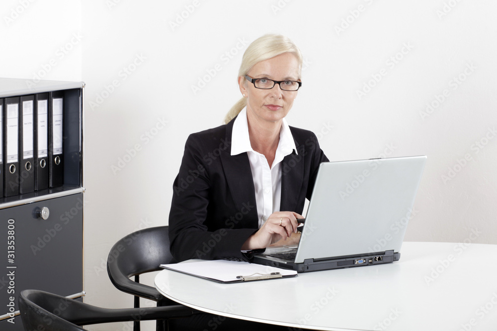 Frau am Schreibtisch mit Laptop nachdenklich Frau am Schreibtisch mit Laptop nachdenklich