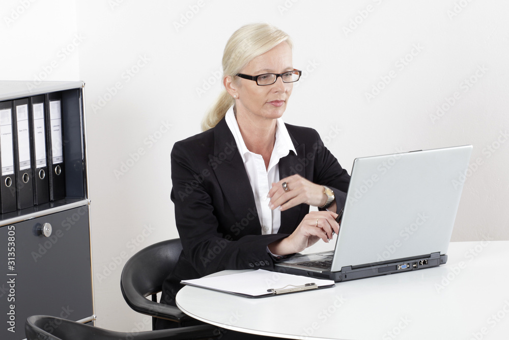 Frau am Schreibtisch mit Laptop und Brille Frau am Schreibtisch mit Laptop und Brille