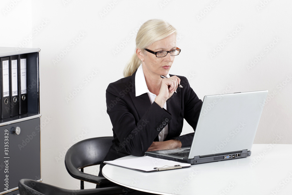 Frau am Schreibtisch mit Laptop im Businessoutfit Frau am Schreibtisch mit Laptop im Businessoutfit
