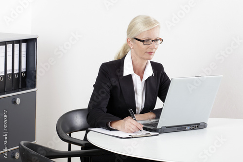 Frau am Schreibtisch mit Laptop schreibend