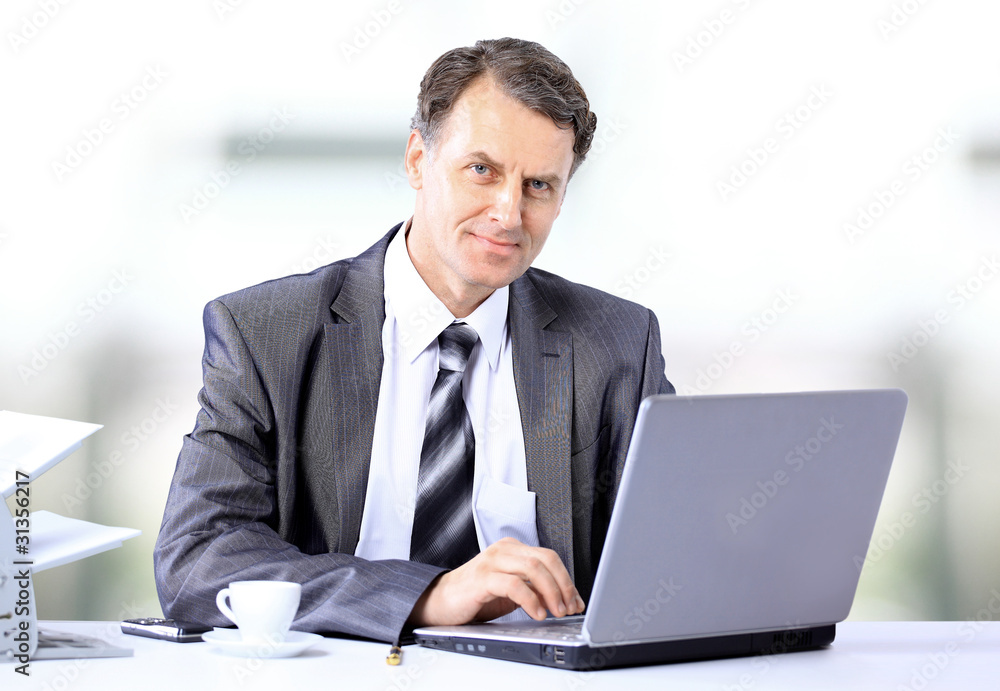 Businessman sitting at desk and working with laptop computer. Businessman sitting at desk and working with laptop computer.