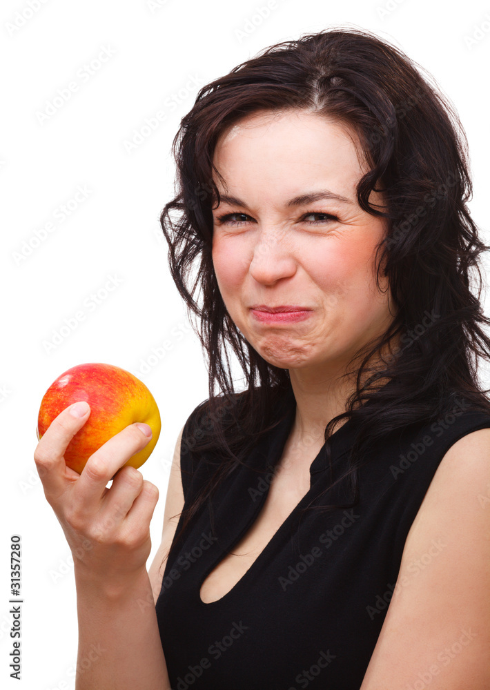 Woman is making sour face after biting an apple Woman is making sour face after biting an apple