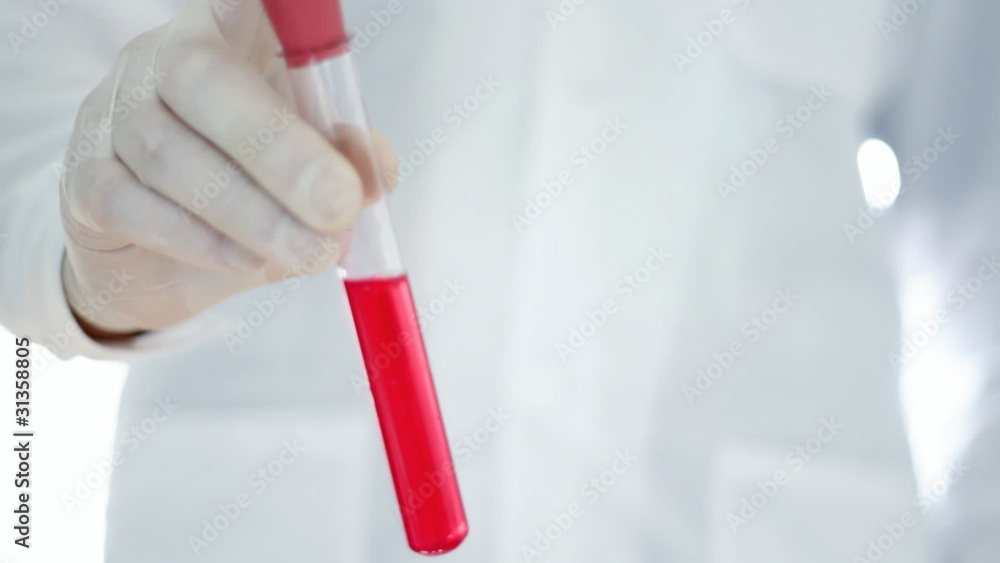 Scientist hand in rubber glove shaking test tube, red substance Scientist hand in rubber glove shaking test tube, red substance