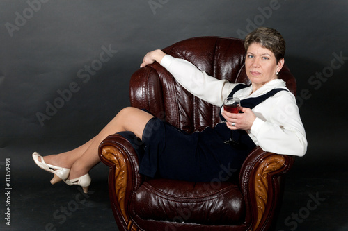 woman seated in a leather chair with glass of wine