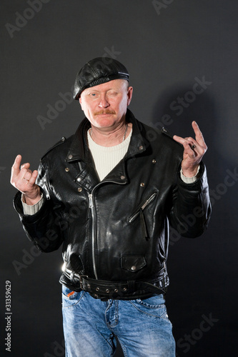 Middle-aged male dressed in leather posing as biker in studio