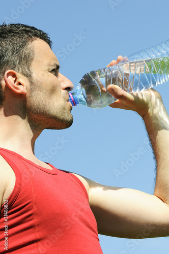Man is drinking water against blue sky