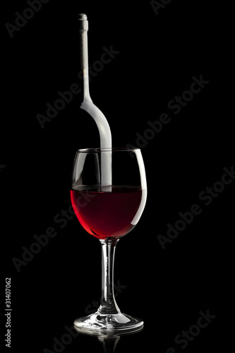 Elegant red wine glass and a wine bottle in black background