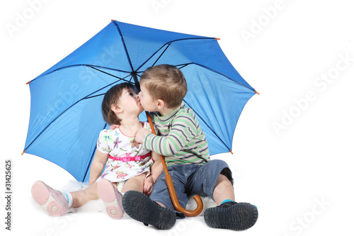 brother and the sister sit under a blue umbrella
