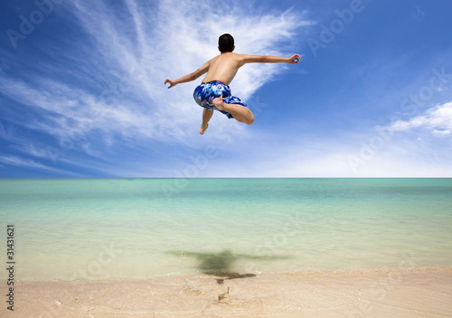 Happy young man jumping on the beach