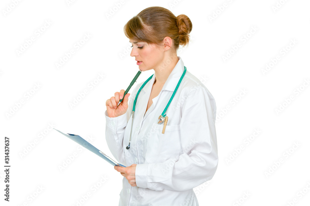 Concentrated female medical doctor looking in medical chart Concentrated female medical doctor looking in medical chart