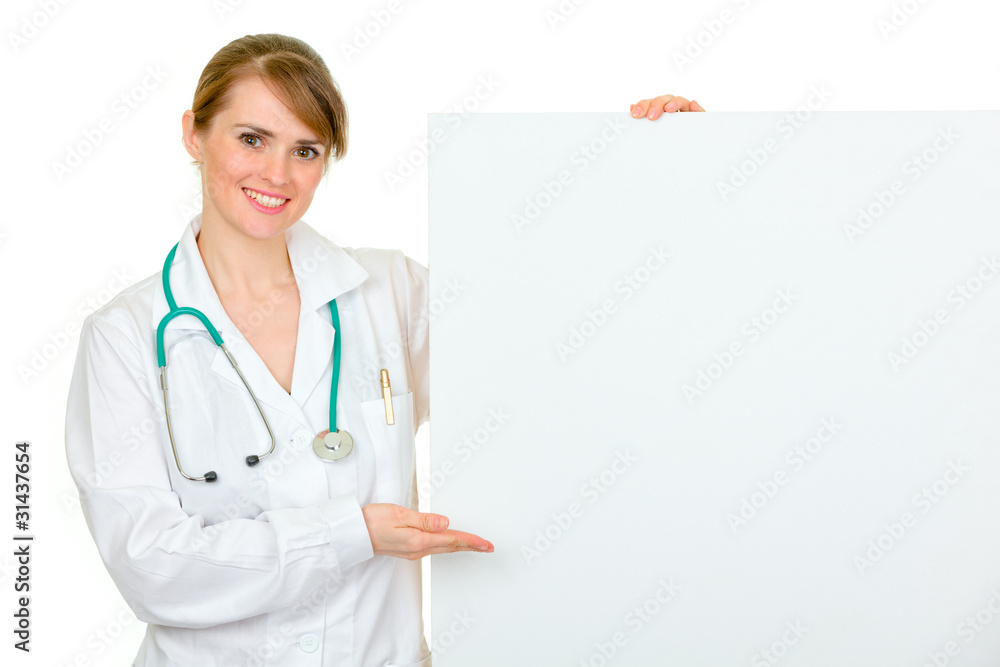Smiling medical doctor woman pointing on blank billboard Smiling medical doctor woman pointing on blank billboard