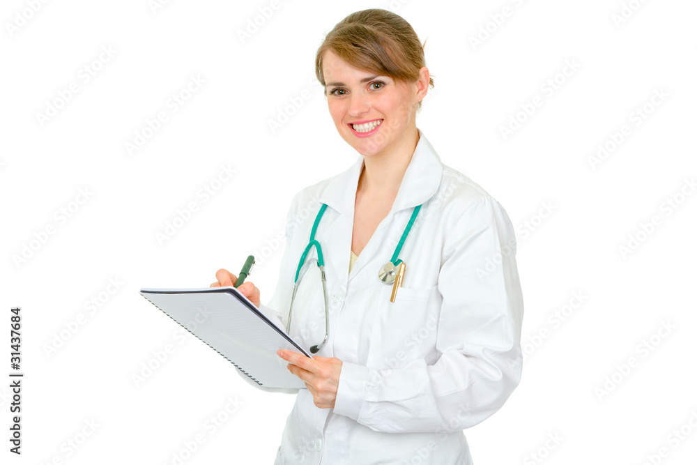Smiling female medical doctor making notes in notebook Smiling female medical doctor making notes in notebook