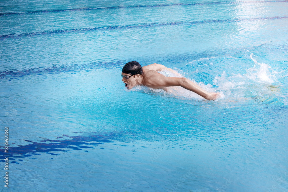 Swimmer in cap and goggles   performing the butterfly stroke