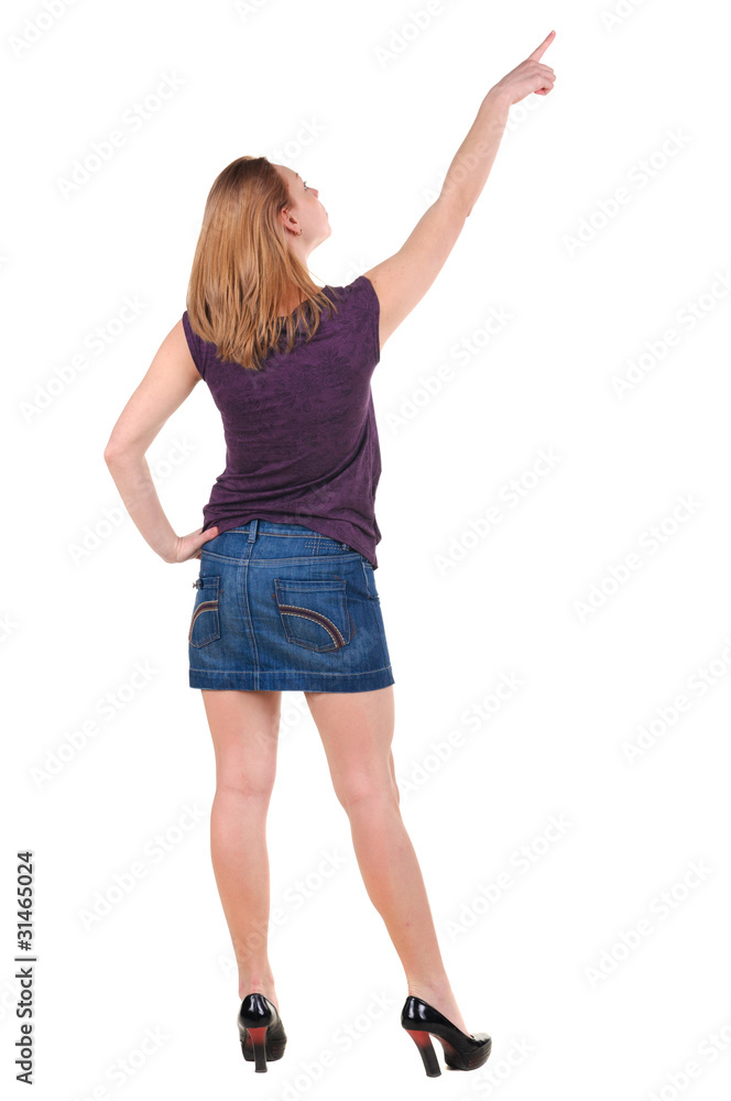Beautiful young woman in dress pointing at wall. Rear view. Beautiful young woman in dress pointing at wall. Rear view.