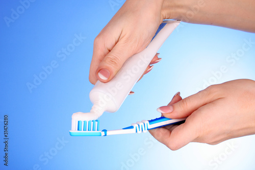 Tooth-paste and brush in the  hand on blue background