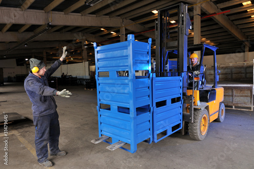 Worker helps forklift operator at factory. © uwimages
