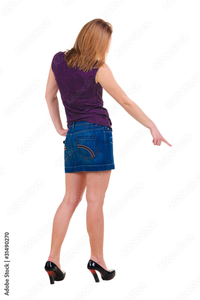 Beautiful young woman in dress pointing at wall. Rear view. Beautiful young woman in dress pointing at wall. Rear view.