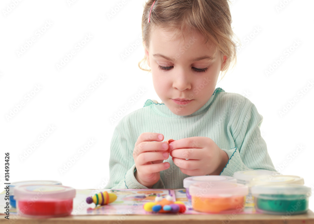 Little girl sitting at table and carefully sculpts figures Little girl sitting at table and carefully sculpts figures