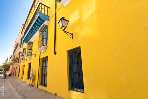 Street in Old Havana with a colorful yellow wall © kmiragaya
