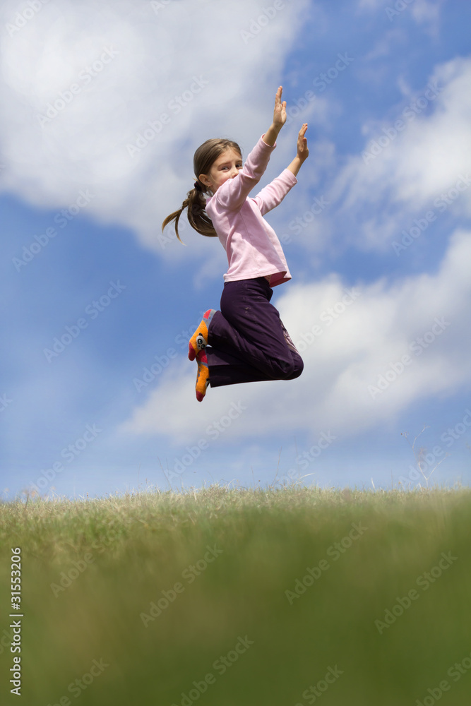 Girl jumping on the meadow, with blue sky and clouds in backgrou Girl jumping on the meadow, with blue sky and clouds in backgrou