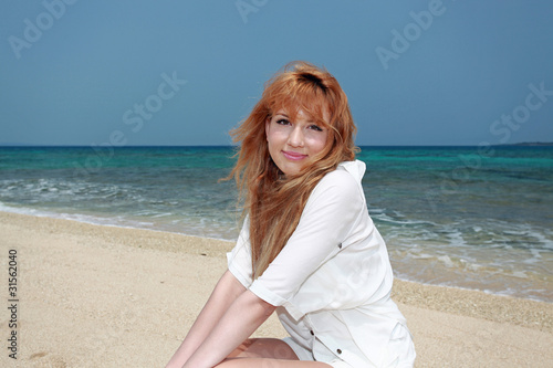 白い砂浜の上に座っている笑顔の女性