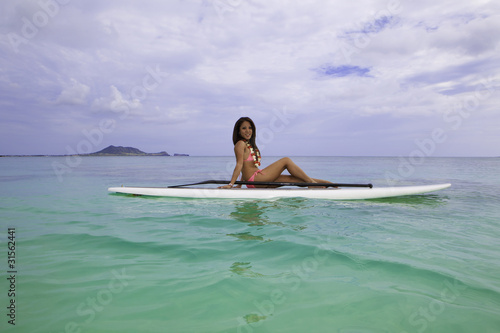 asian woman in pink bikini on a paddle board in hawaii