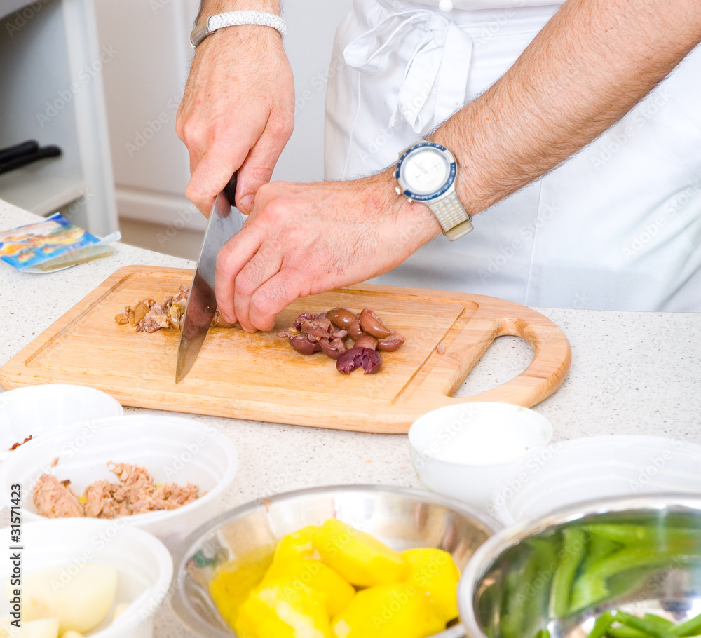 Chef cutting the olives on a wooden board Chef cutting the olives on a wooden board