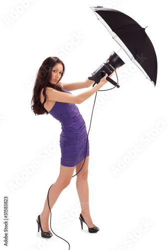 Young pretty lady in blue dress holding studio flash with umbrel photo