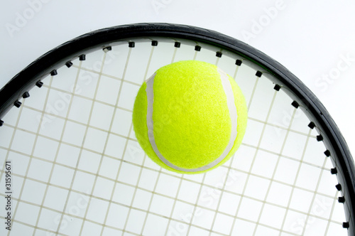 A tennis ball is on the racket and isolated on white background. © anat_tikker