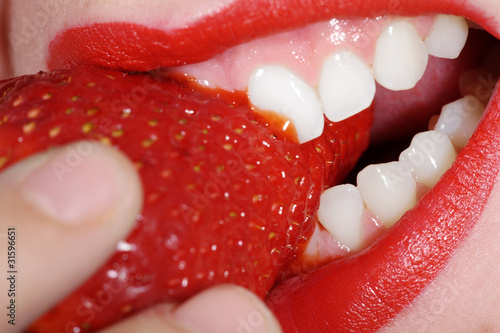 Mund mit roten Lippen beisst in Erdbeere Nahaufnahme