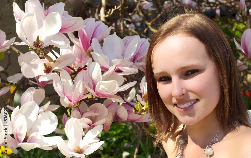Fototapeta premium Frau steht vor einem Magnolienbaum