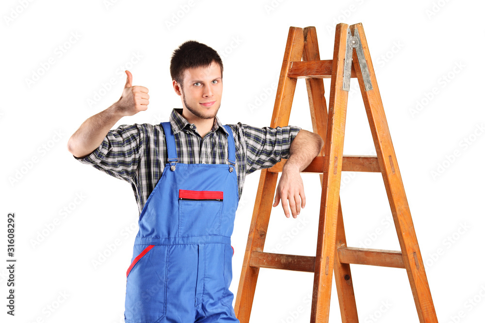 Manual worker standing next to a wooden ladder and giving thumb Manual worker standing next to a wooden ladder and giving thumb