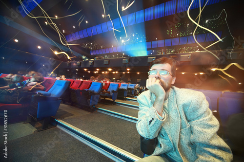 Man sits in cinema and leans chin on an elbow