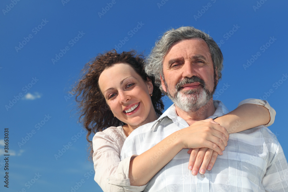 adult daughter embracing father from back and smiling