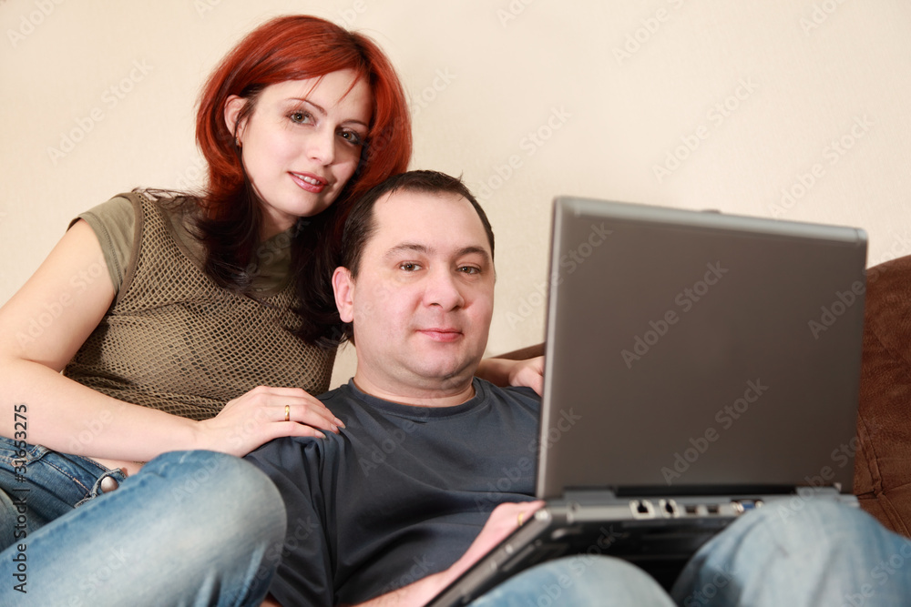 wife and husband sit on sofa and looking at laptop wife and husband sit on sofa and looking at laptop