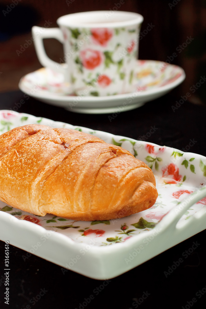 croissant on the plate with tea cup
