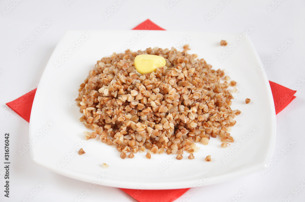 Appetizing crumbly buckwheat with butter on white background Appetizing crumbly buckwheat with butter on white background