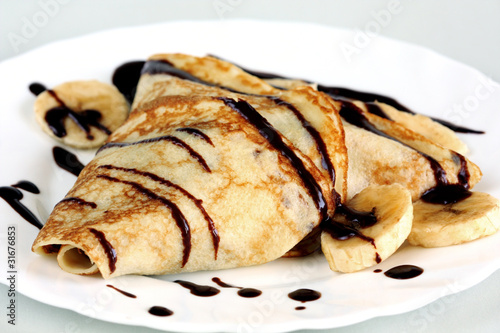 close-up crepe with bananas and chocolate on white plate
