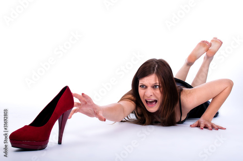 Beautiful young woman trying to reach her high heels