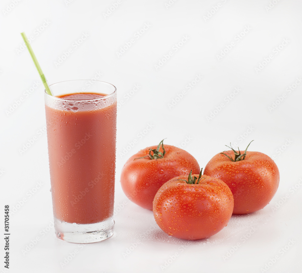 Fresh tomatoes and a glass full of tomato juice on white Fresh tomatoes and a glass full of tomato juice on white