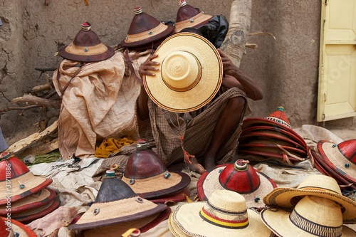 An African hat seller covering his face with a hat © fadamson