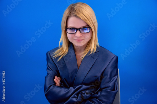 confident girl in glasses sitting on blue background